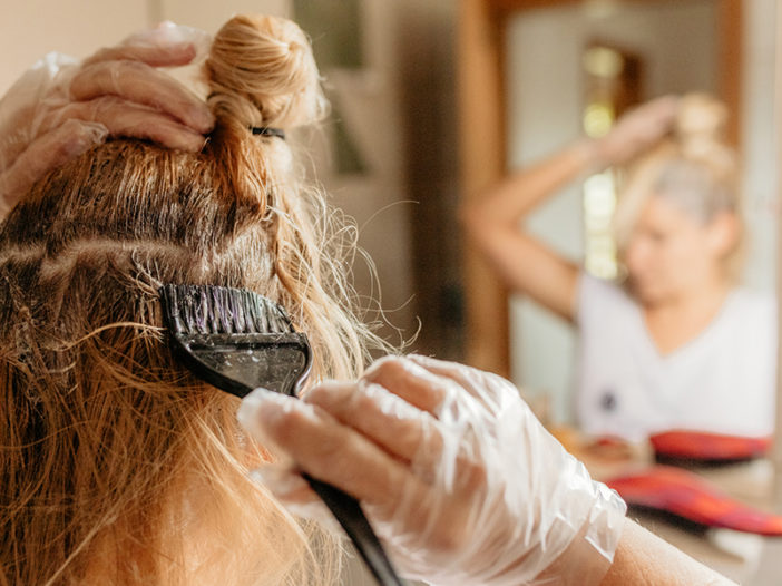 Woman dyeing hair in front of mirror