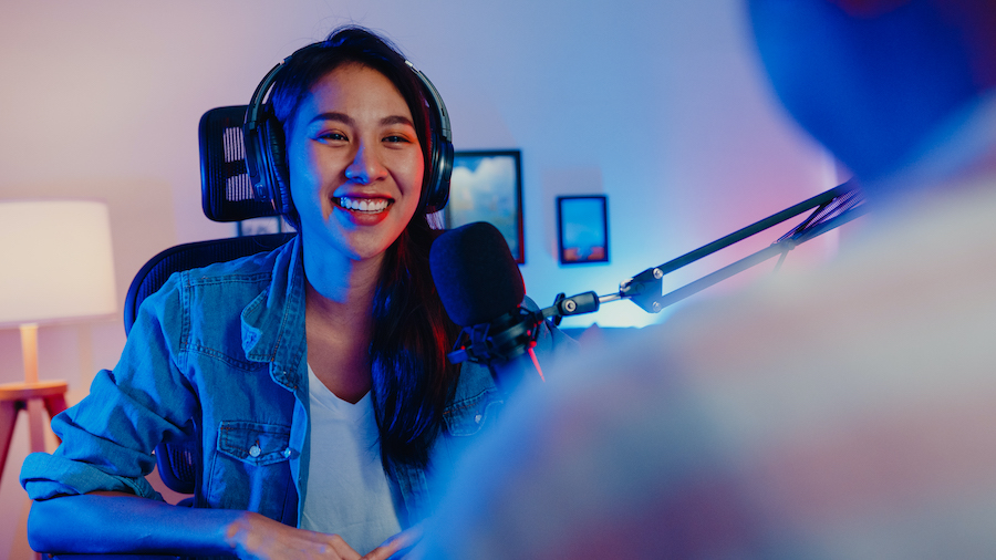 Young woman wearing headphones behind a podcasting or streaming microphone