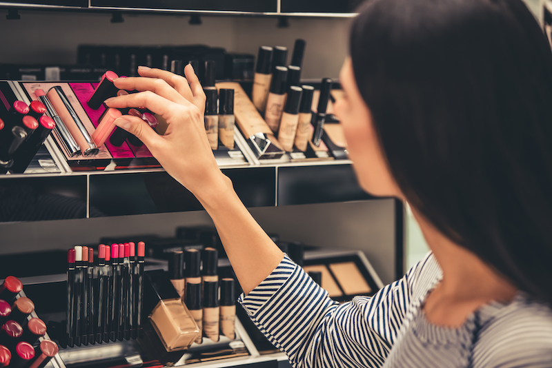 A woman selecting lipstick from a store display shelf