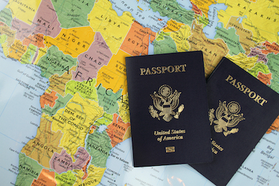 Two US passports resting on a colorful map of the world