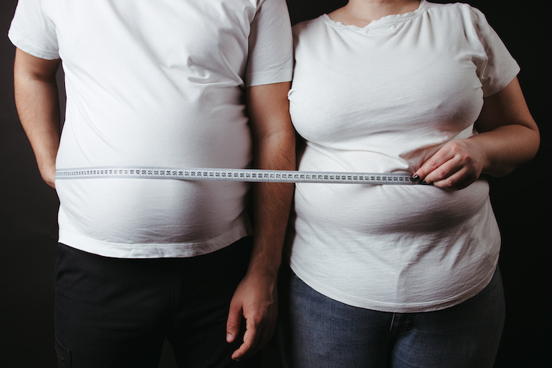 Man and woman in white tee shirts with rulers around their waists