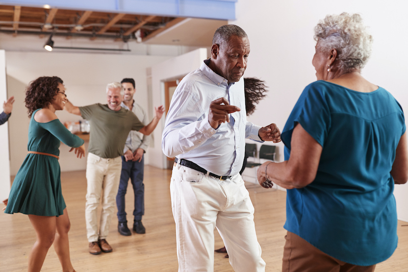 A senior couple dancing in a studio along with middle-aged couples
