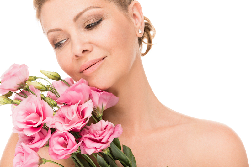 A woman holds a bouquet of pink roses against her skin