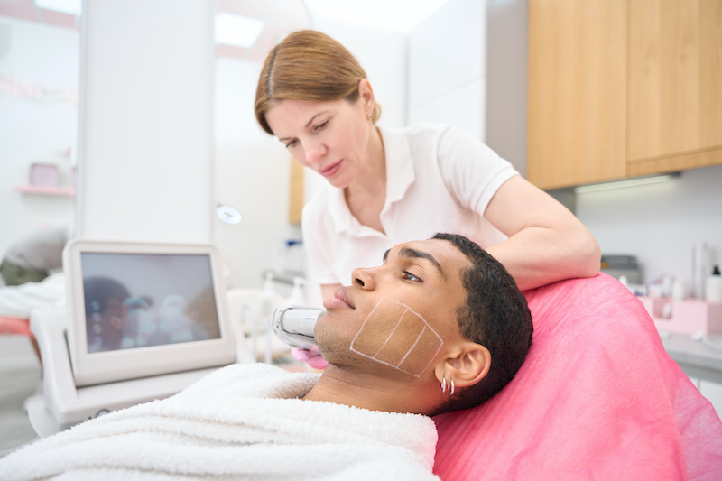 Man laying in a medical office receiving laser skin treatment