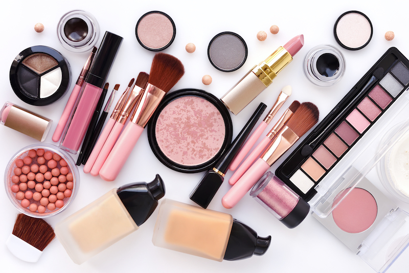 Lipstick, blushes, and various other makeup products scattered on a white surface