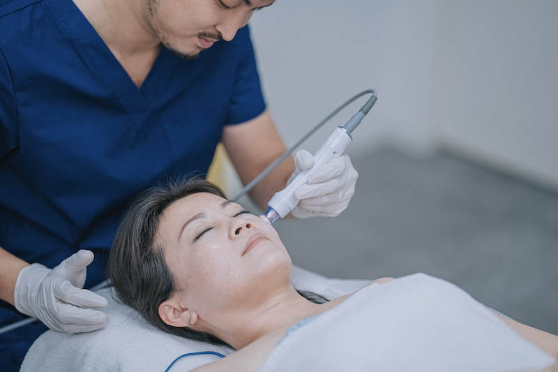 A woman laying down receiving laser skin rejuvenation treatment on her face
